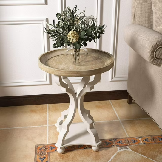 A rustic farmhouse cottagecore accent end table with a natural tray top, holding a vase with a floral arrangement.