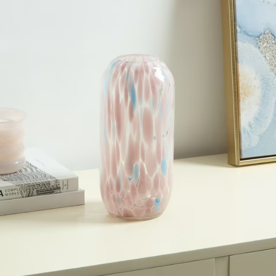 A clear glass cylinder vase with speckled or painted designs in shades of pink and light blue." 