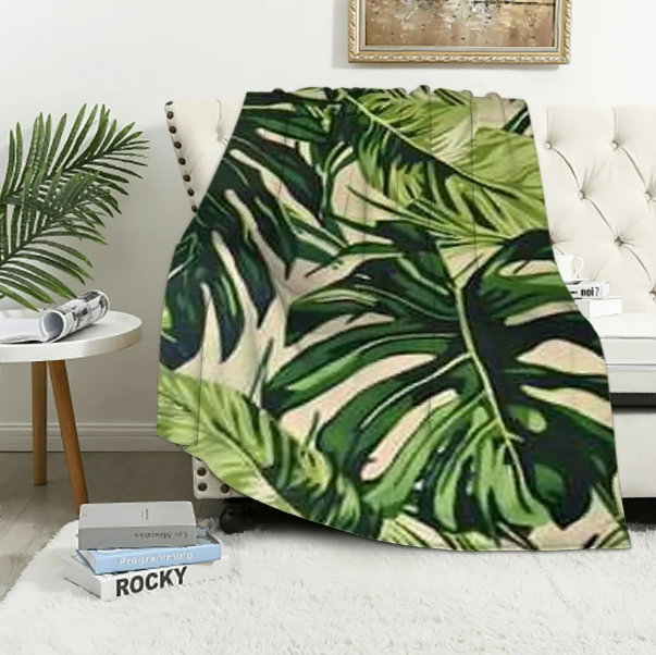 A throw blanket featuring a vibrant pattern of green tropical palm leaves.