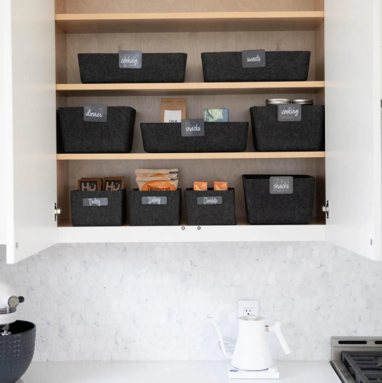 Organized pantry cabinet featuring black felt storage bins with labels.