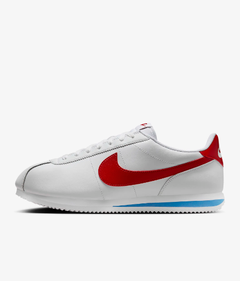 A white Nike Cortez sneaker with a prominent red swoosh logo on the side, a blue stripe on the midsole, and a red accent on the heel.